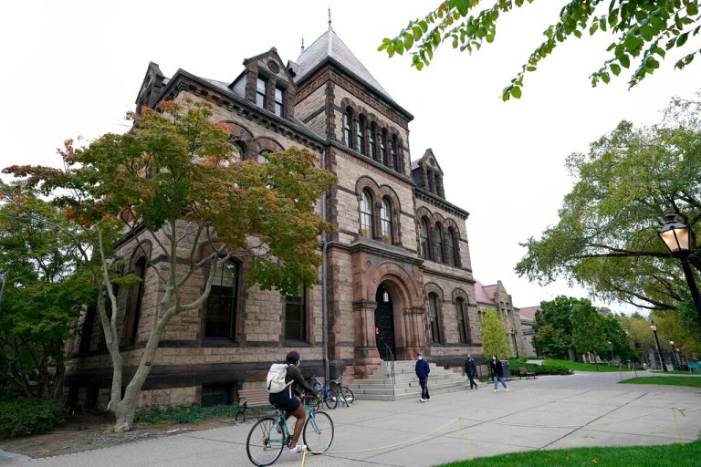 Passers-by walk and ride along a path on the campus of Brown University, in Providence, R.I., Monday, Oct. 12, 2020. 