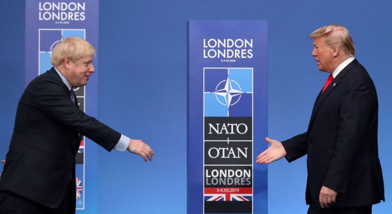 In this Dec. 4, 2019 file photo British Prime Minister Boris Johnson, left, reaches out to shake hands with U.S. President Donald Trump at the official arrivals for a NATO leaders meeting at The Grove hotel and resort in Watford, Hertfordshire, England.