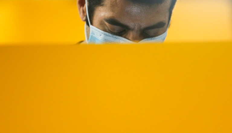 A voter wearing a face mask casts his ballot at vote center in SoFi Stadium during the Election Day, Tuesday, Nov. 3, 2020, in Inglewood, Calif.