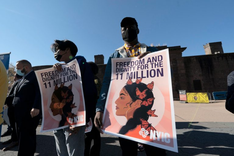 Isaiah Buffong holds a sign at a rally, Monday, Nov. 9, 2020, in New York. Those at the rally are asking  Joe Biden to prioritize immigration reform.