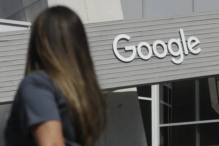 A woman walks below a Google sign.
