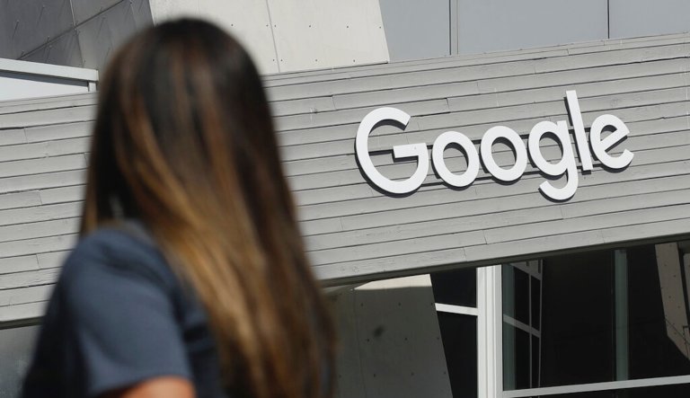 In this Sept. 24, 2019, file photo a woman walks below a Google sign on the campus in Mountain View, Calif.