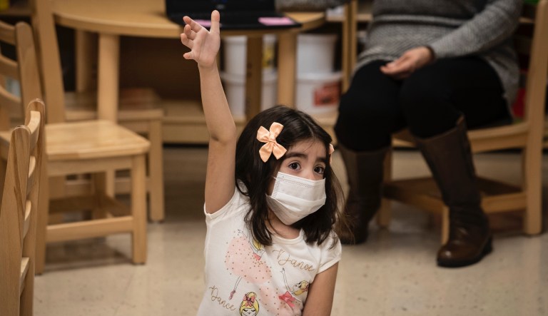 A preschool student raises her hand during class at Dawes Elementary School in Chicago, Monday, Jan. 11, 2021.