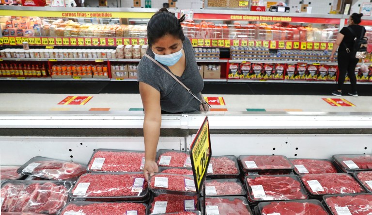 In this April 29, 2020 file photo, amid concerns of the spread of COVID-19, a shopper wears a mask as she looks over meat products at a grocery store in Dallas.