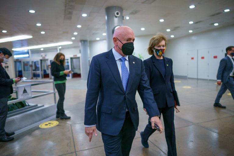 Sen. Mark Kelly, D-Ariz., left, and Sen. Tammy Baldwin, D-Wis., walk to the chamber where Vice President Kamala Harris swore in two new senators from Georgia, at the Capitol in Washington, Wednesday, Jan. 20, 2021. Kelly said during a television interview that it is 