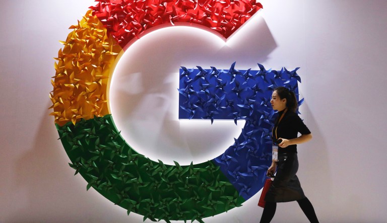 In this Monday, Nov. 5, 2018 file photo, a woman walks past the logo for Google at the China International Import Expo in Shanghai.