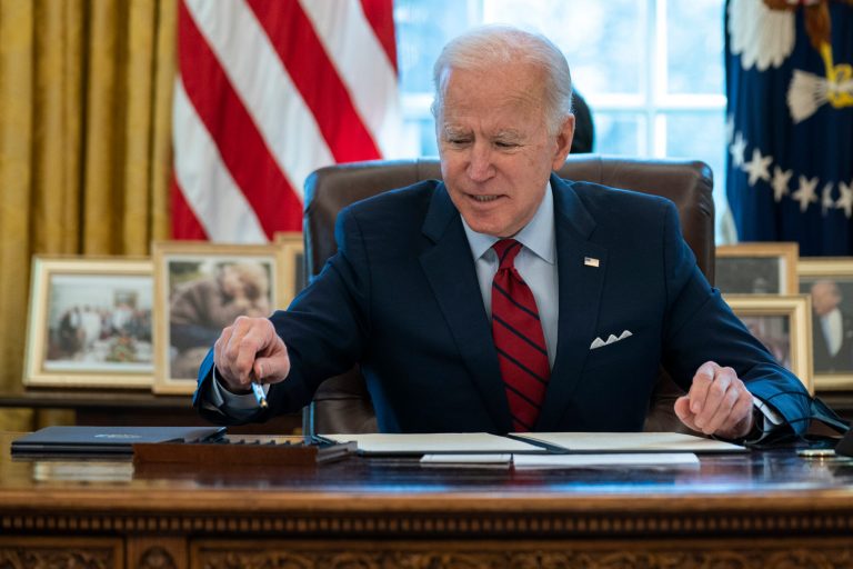 President Joe Biden reaches for a pen before signing a series of executive orders on health care, in the Oval Office of the White House, Thursday, Jan. 28, 2021, in Washington. 