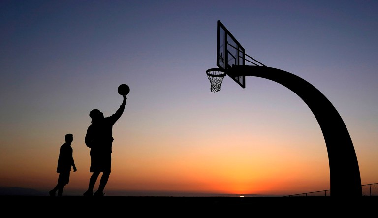 Visitors shoot a ball on a basketball court as the sun sets at Angels Gate Park Wednesday, Feb. 10, 2021, in the San Pedro section of Los Angeles. 