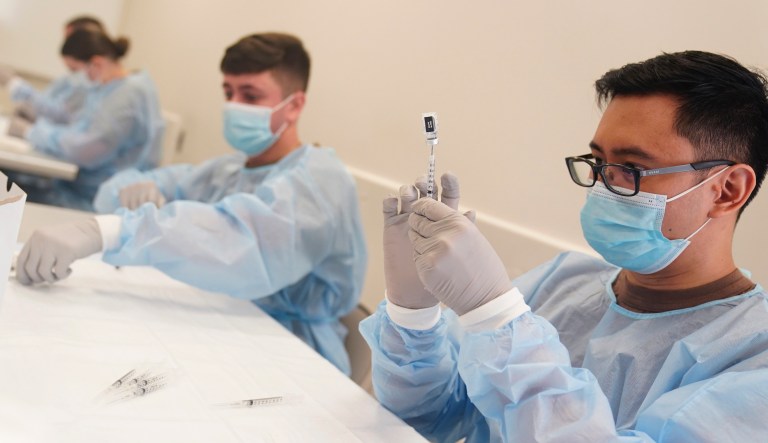 Navy personnel prepare doses of the COVID-19 vaccine before the opening of a mass vaccination site in the Queens borough of New York, Wednesday, Feb. 24, 2021.