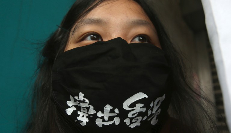 A Hong Kong protester living in Taiwan wears a mask with slogan "Stay out of Hong Kong" as Hong Kong democracy activists are headed to court for second day, in Taipei, Taiwan, Tuesday, March 2, 2021. A court hearing for 47 democracy activists charged under Hong Kong's national security law was set to resume Tuesday after a marathon session that was adjourned well past midnight after one defendant appeared to collapse and was taken away in an ambulance.