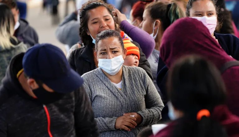 A woman waits for food handouts from a local church at a makeshift camp for migrants seeking asylum in the United States at the border crossing Friday, March 12, 2021, in Tijuana, Mexico.