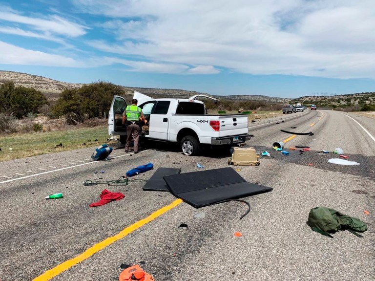 Debris is strewn across a road near the border city of Del Rio, Texas, after a collision on March 15, 2021. Eight people in a pickup truck loaded with immigrants were killed when the vehicle collided with an SUV following a police chase, authorities said. 