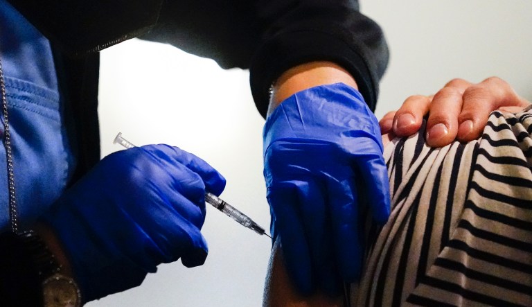A health worker administers a dose of a Pfizer COVID-19 vaccine during a vaccination clinic at the Grand Yesha Ballroom in Philadelphia, Wednesday, March 17, 2021.