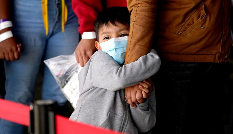 A migrant child holds onto a womanâs arm as they wait to be processed by a humanitarian group after being released from U.S. Customs and Border Protection custody at a bus station, Wednesday, March 17, 2021, in Brownsville, Texas.
