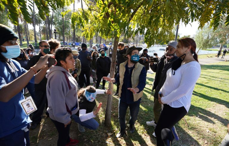 An Echo Park resident is surrounded by activists as she argues with some of remaining residents of the Echo Park homeless encampment at Echo Park Lake in Los Angeles Wednesday, March 24, 2021. (AP Photo/Damian Dovarganes)