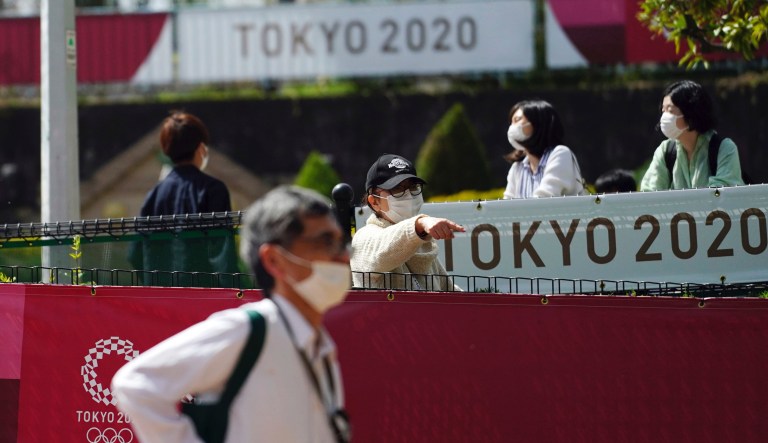 People wearing protective masks to help curb the spread of the coronavirus walk near banners for Tokyo 2020 Olympic and Paralympic Games Wednesday, March 31, 2021, in Tokyo. The Japanese capital confirmed more than 410 new coronavirus cases on Wednesday.