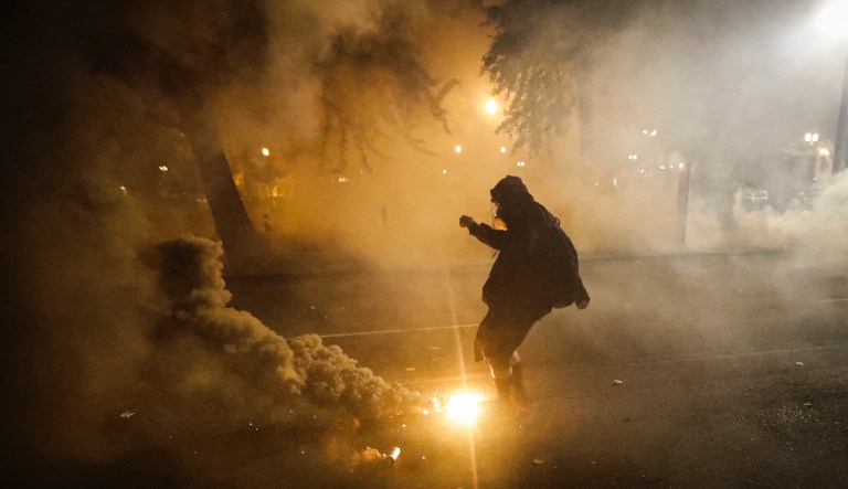 In this July 29, 2020, file photo, a demonstrator kicks a tear gas canister back at federal officers during a Black Lives Matter protest at the Mark O. Hatfield U.S. Courthouse in Portland, Ore.