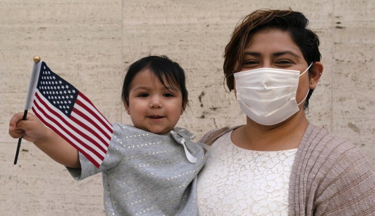 One-year-old Emily Reyes holds a United States flag after her mother Laura Reyes, originally from Mexico, became an American citizen, Wednesday, April 28, 2021 in New York.