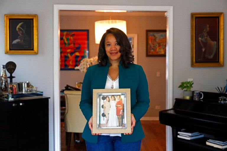 Robin Rue Simmons, poses for a portrait holding a photograph of her mother, aunt, and grandmother in her home in Evanston, Ill., Friday, April 9, 2021. (AP Photo/Shafkat Anowar)