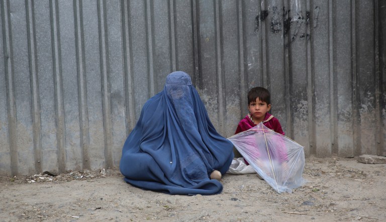 In this May 2, 2020 file photo, a woman waits to receive alms with her daughter during the Muslim fasting month of Ramadan in Kabul, Afghanistan.