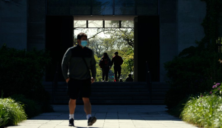 Students and pedestrians make their way through the University of Chicago campus, Thursday, May 6, 2021. Even as restrictions relax across much of the United States, colleges and universities have taken new steps to police campus life as the virus spreads through students who are among the last adults to get access to vaccines.