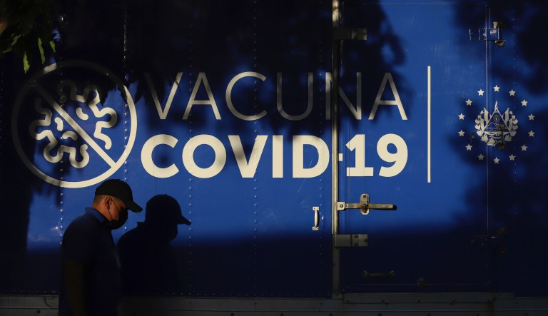 A driver walks past a refrigerated container truck from the Health Ministry that will transport doses of COVID-19 vaccines which El Salvador's government is donating and delivering to neighboring Honduras, shortly before departing San Salvador, El Salvador, Thursday, May 13, 2021.