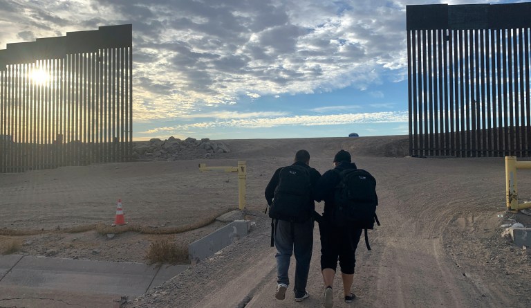 Cuban migrants, Alain Rios, left, gets a helping hand from his wife, Katia Maden, as they walk towards a gap in the border wall in Yuma, Ariz., on June, 9, 2021 to seek asylum in the US. The pair mainly walked over four months from Venezuela before Rios sprained his ankle just steps away from reaching the US. The pair joined dozens of other asylum-seekers this day who passed through the gap to waiting US border patrol agents. 