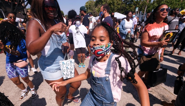People dance as they celebrate during a Juneteenth commemoration at Leimert Park Plaza on Saturday, June 19, 2021, in Los Angeles.