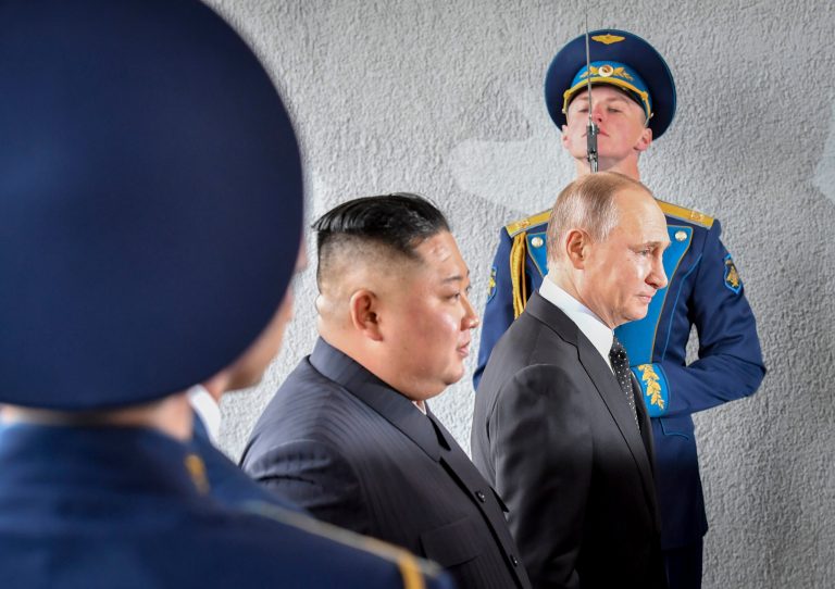 In this Thursday, April 25, 2019, photo, President Vladimir Putin and North Korean leader Kim Jong Un walk past honor guard officers during their meeting in Vladivostok, Russia.
