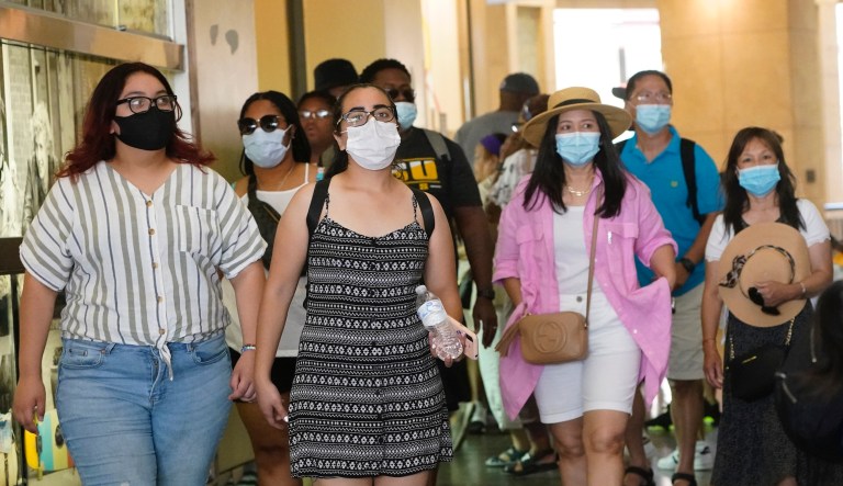 In this July 1, 2021, file photo visitors wear masks as they walk in a shopping district in the Hollywood section of Los Angeles. A rapid and sustained increase in COVID-19 cases in the nation's largest county requires restoring an indoor mask mandate even when people are vaccinated, Los Angeles County's public health officer said Thursday, July 15, 2021.