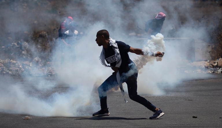 A Palestinian protester hurl back a tear gas canister fired by Israeli forces during a protest over the killing of four Palestinians in Jenin refugee Camp by Israeli forces on Monday, at the northern entrance of the West Bank city of Ramallah, Tuesday, Aug. 17, 2021.