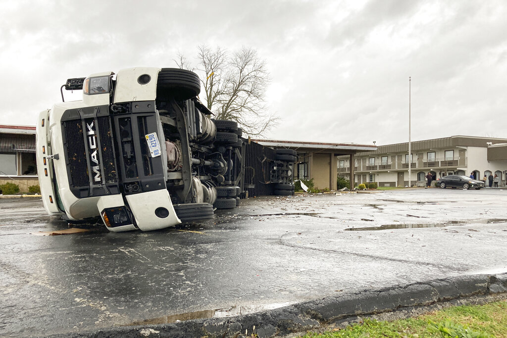 A large semi-trailer is flipped over and pushed against a building in Bowling Green, Kentucky, on Saturday after a major storm.