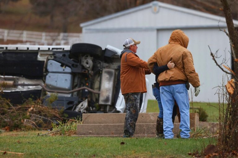 People embrace outside their home that has been heavily damaged by a possible tornado Saturday in Defiance, Missouri.