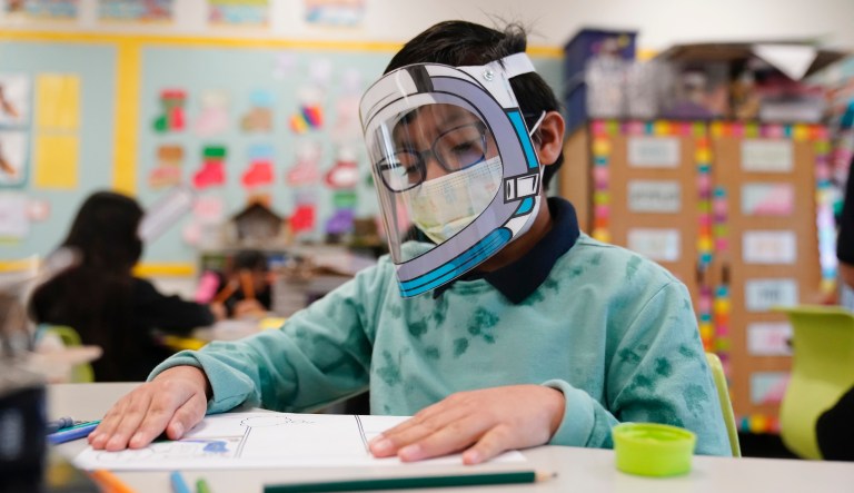 A student wears a mask and face shield in a 4th grade class amid the COVID-19 pandemic at Washington Elementary School Wednesday, Jan. 12, 2022, in Lynwood, Calif.