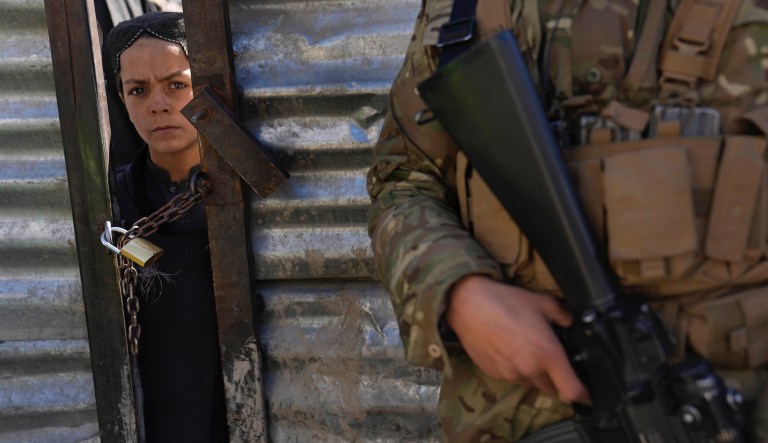 An Afghan boy looks through a locked door, as he waits his turn to receive food supplies during a distribution of humanitarian aid for families in need, in Kabul, Afghanistan, Wednesday, Feb. 16, 2022.