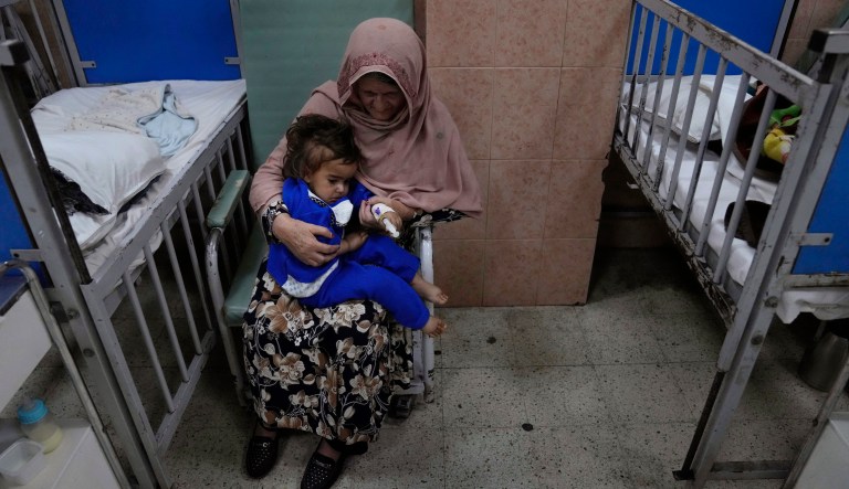 An Afghan woman holds her sick granddaughter, where she undergoes treatment in the malnutrition ward of the Indira Gandhi Children's Hospital, in Kabul, Afghanistan, Thursday, Feb. 24, 2022.
