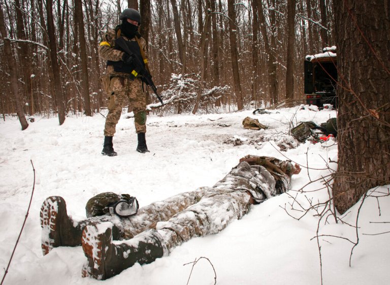 A volunteer of the Ukrainian Territorial Defense Forces looks at a dead body of a soldier lying in a forest in the outskirts of Kharkiv, Ukraine's second-largest city, Monday, March 7, 2022.