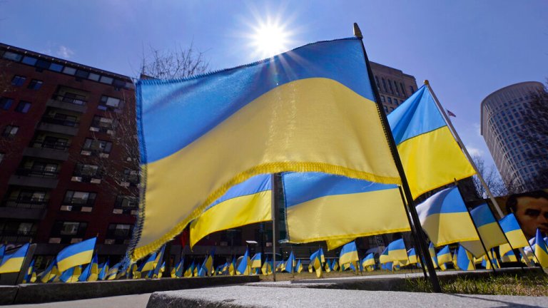 The sun peers over hundreds of Ukraine flags flying in support of the Ukrainian people, Wednesday, March 16, 2022, in Boston. 