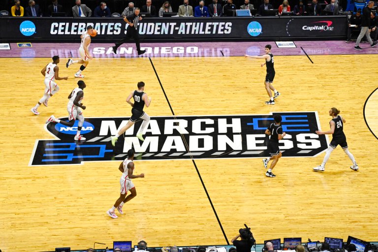 Arizona and Wright State players move past the March Madness logo during the first half of a first-round NCAA college basketball tournament game, Friday, March 18, 2022, at Viejas Arena in San Diego.