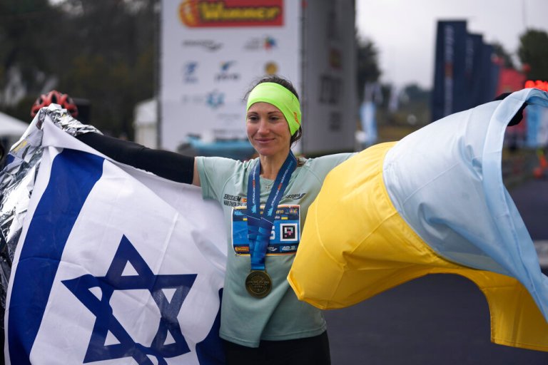 Ukrainian runner Valentyna Veretska poses with the Ukrainian and Israeli flags after finishing first among the female group in the Jerusalem marathon in Jerusalem, Friday, March 25, 2022. 