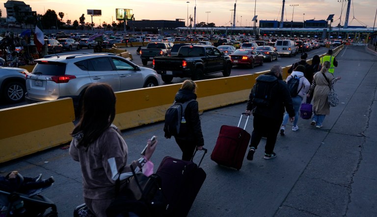 Ukrainian refugees follow a volunteer to the San Ysidro Port of Entry as they prepare to cross the border Monday, April 4, 2022, in Tijuana, Mexico. About 200 to 300 Ukrainians were being admitted daily at the San Ysidro crossing this week, with hundreds more arriving in Tijuana, according to volunteers who manage the waiting list. There were 973 families or single adults waiting on Tuesday. 