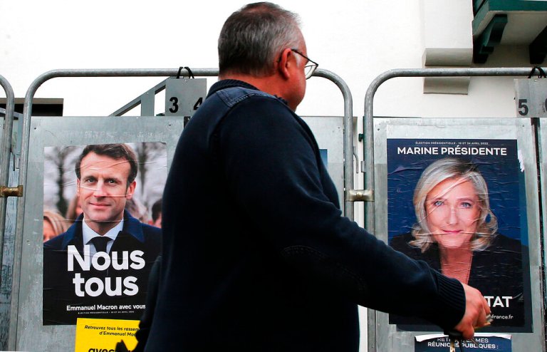 A man walks past presidential campaign posters of French President Emmanuel Macron and French far-right presidential candidate Marine Le Pen in Anglet, France, on Wednesday.