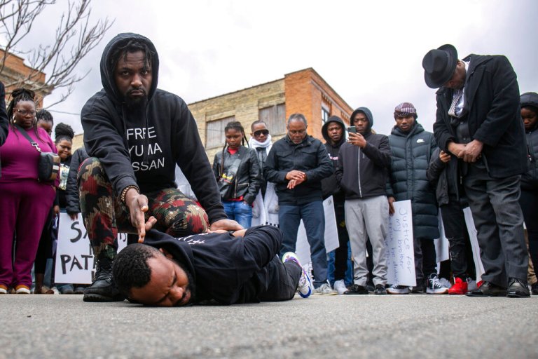 A moment of silence is held as two activists act out how the family of 26-year-old Patrick Lyoya says he was killed in an unreleased video at the end of the Justice for Patrick Lyoya march in Grand Rapids, Michigan, on Saturday, April 9, 2022. 