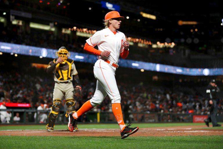 San Francisco Giants' first base coach Alyssa Nakken runs to get in position, near San Diego Padres catcher Austin Nola, left, during the third inning of a baseball game in San Francisco, Tuesday, April 12, 2022. 