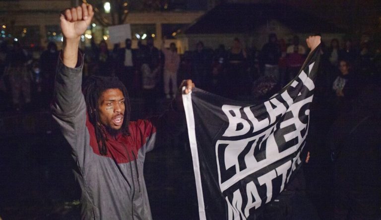 Protesters carrying a Black Lives Matter flag march inside a fountain at Veterans Memorial Park.