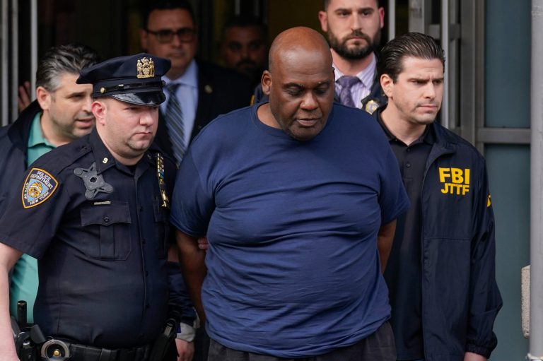 Law enforcement officials lead subway shooting suspect Frank R. James, 62, center, away from a police station in New York, Wednesday, April 13, 2022. The man accused of shooting multiple people on a Brooklyn subway train was arrested Wednesday and charged with a federal terrorism offense.