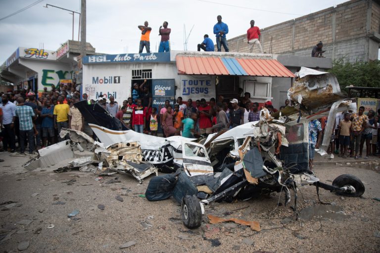 Onlookers mill around the wreckage of a small plane that crashed in the community of Carrefour, Port-au-Prince, Haiti, Wednesday, April 20, 2022. Police report that the plane was headed to the southern coastal city of Jacmel when it tried to land in Carrefour and that at least five people died in the accident.