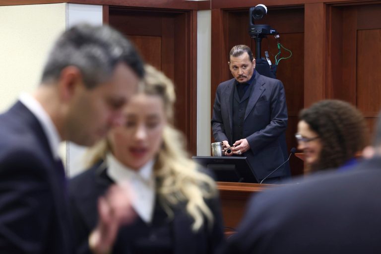 Actor Amber Heard speaks with her legal team as actor Johnny Depp stands at the Fairfax County Circuit Court in Fairfax, Virginia, on Thursday.