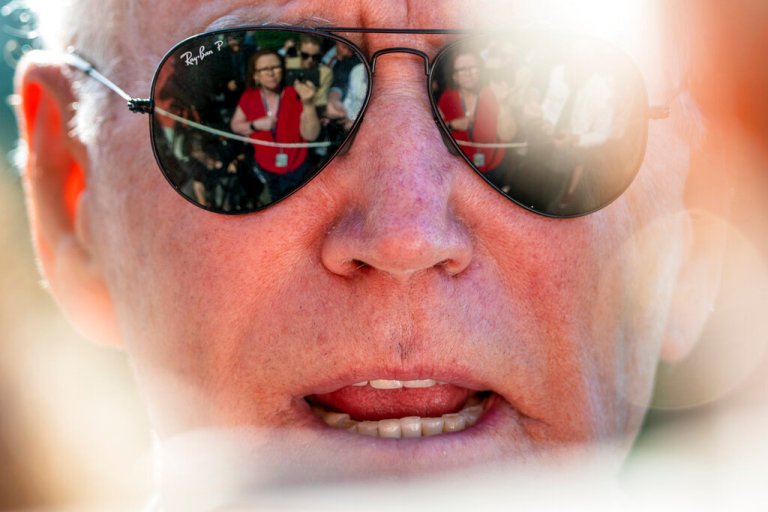 Members of the media are visible in the sunglasses of President Joe Biden as he speaks on the South Lawn of the White House in Washington, Monday, May 30, 2022, after returning from Wilmington, Del.