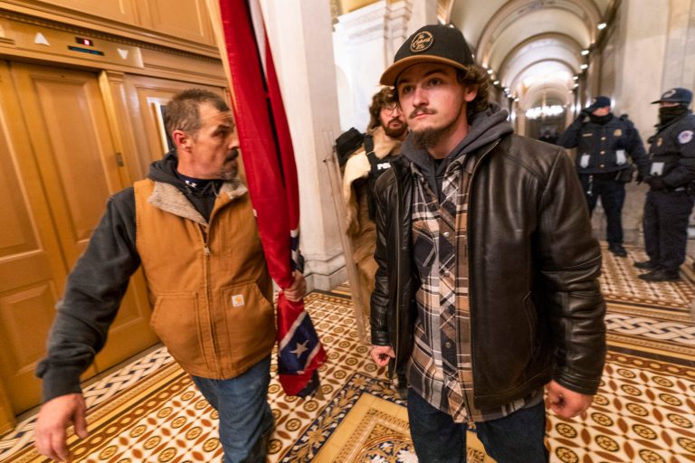 FILE - Insurrectionists loyal to President Donald Trump, including Kevin Seefried, left, walk on a hallway after a confrontation with Capitol Police officers outside the Senate Chamber inside the Capitol, Jan. 6, 2021 in Washington.